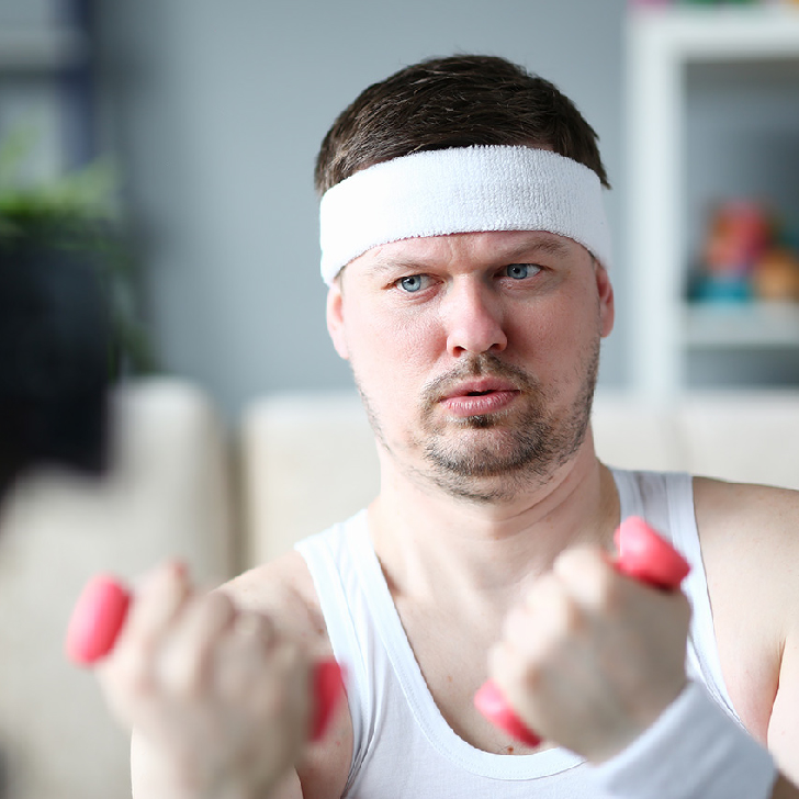 Harry smith wearing a headband and lifting comically small pink weights